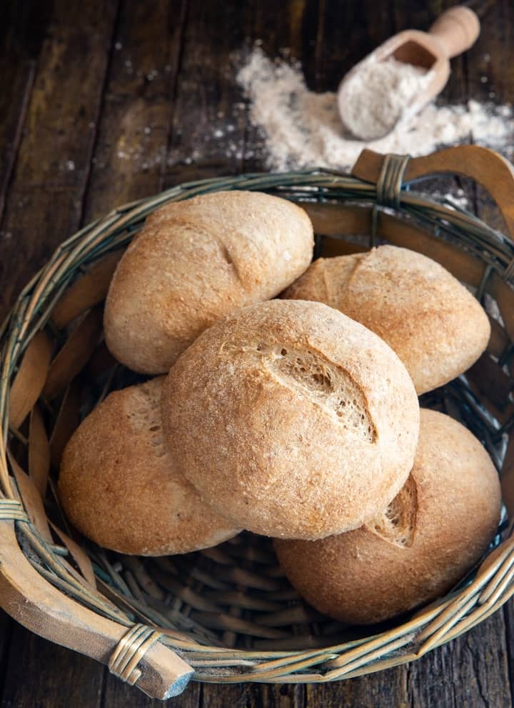 Sourdough whole wheat buns in a basket.