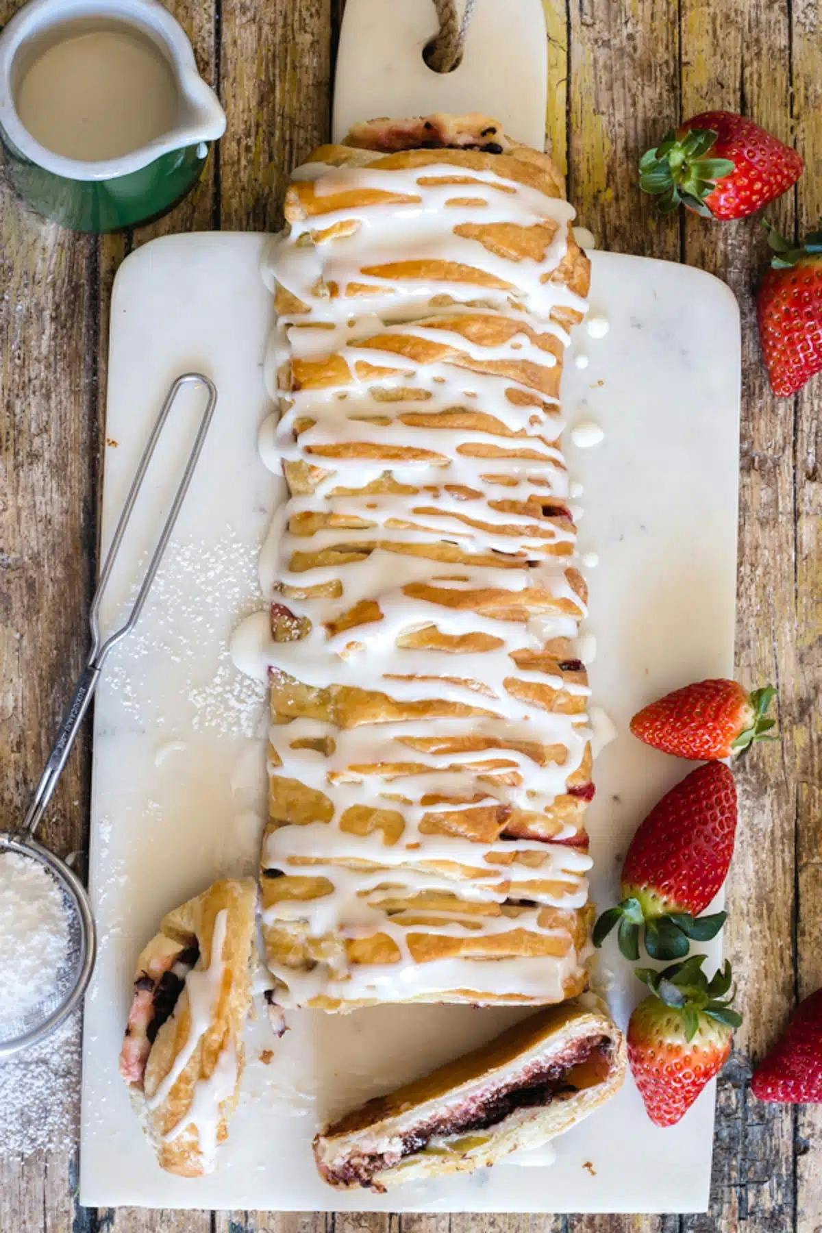 Strawberry strudel with two slices cut on a white board.