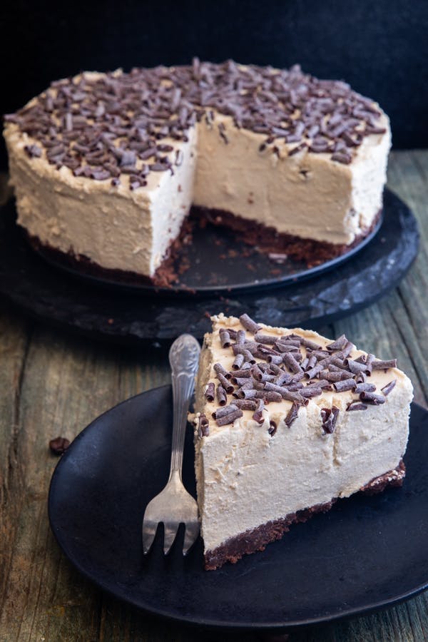 No bake coffee cheesecake on a black plate with a slice on a small black plate.