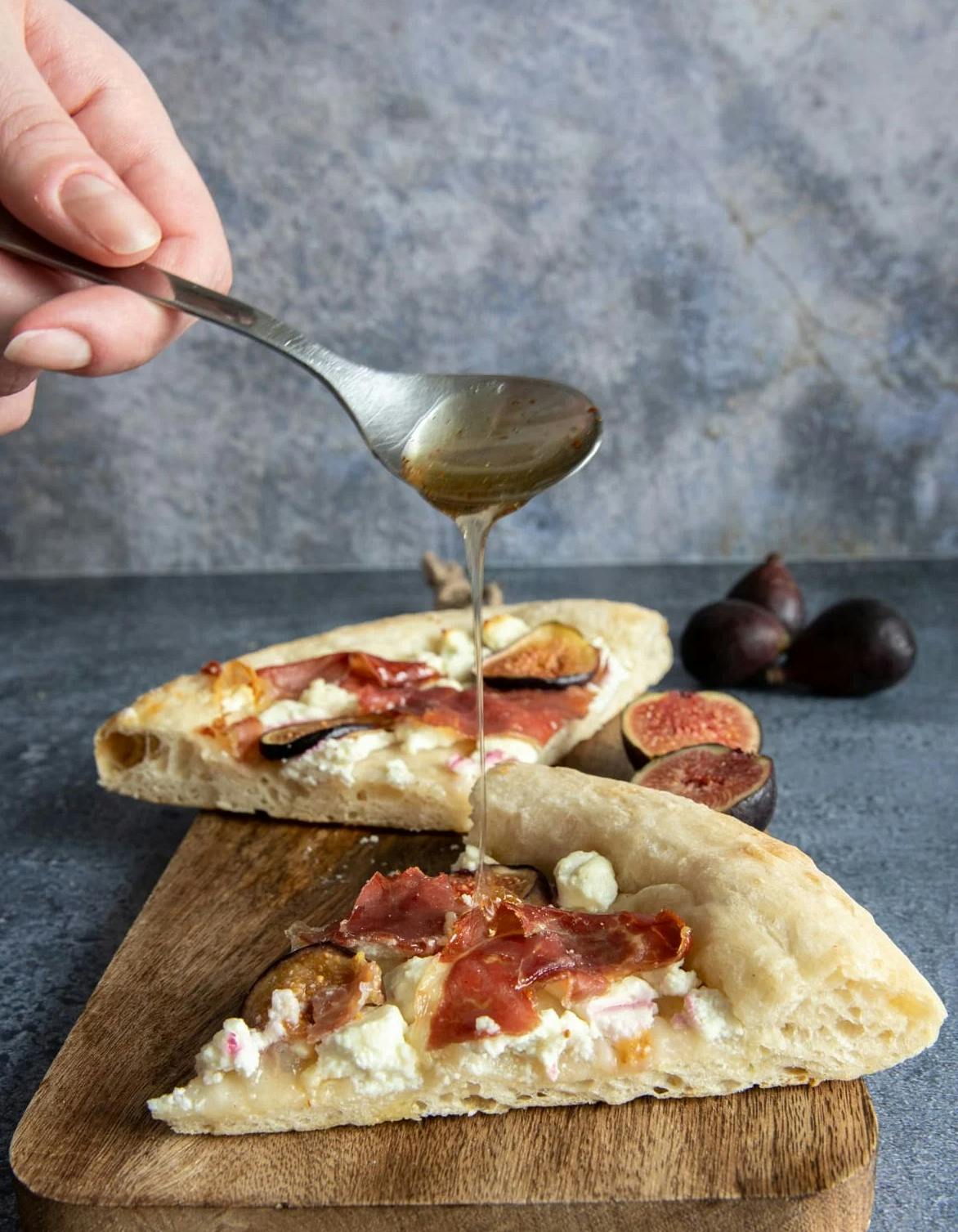 Pouring honey on a fig pizza.