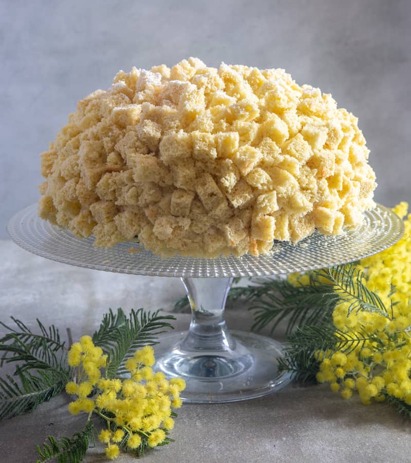 Mimosa cake on a glass cake stand.