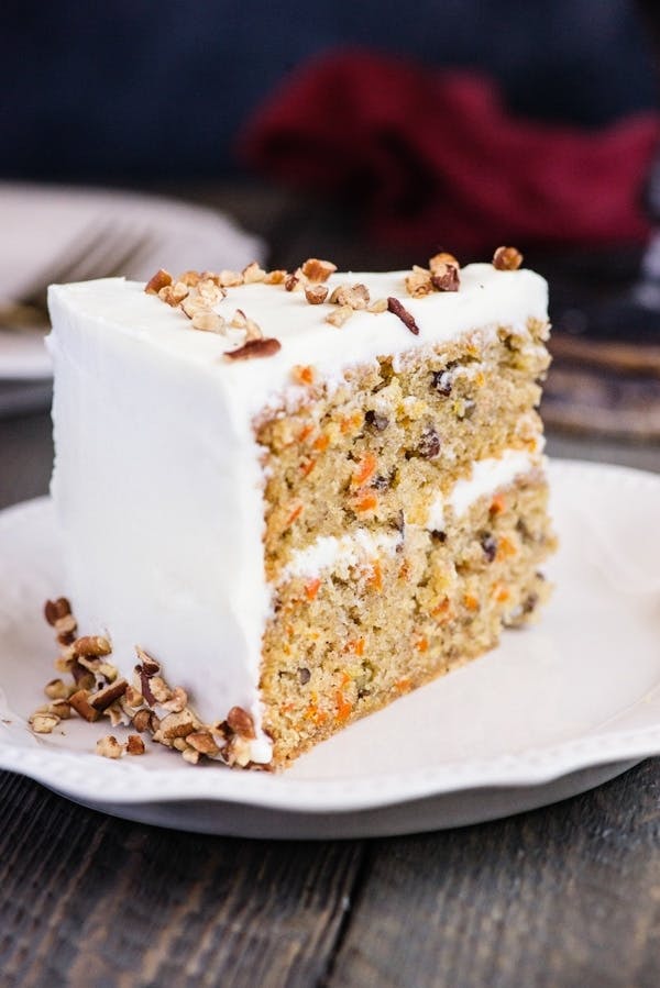 Homemade carrot cake slice on a white plate.