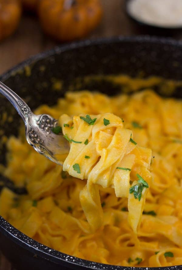 Creamy pumpkin pasta sauce with pasta and some on a fork.