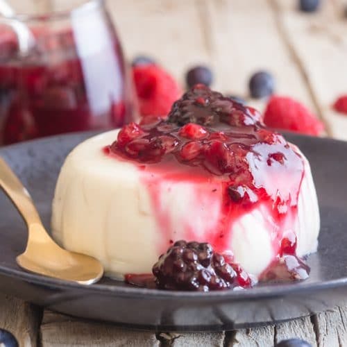 a slice of panna cotta on a black plate.