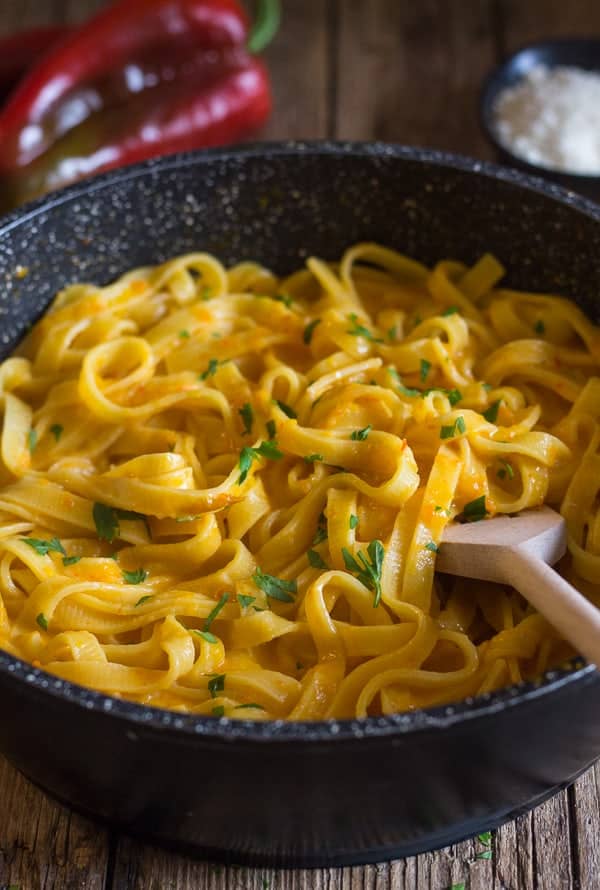Red pepper sauce ad pasta in a black pan.