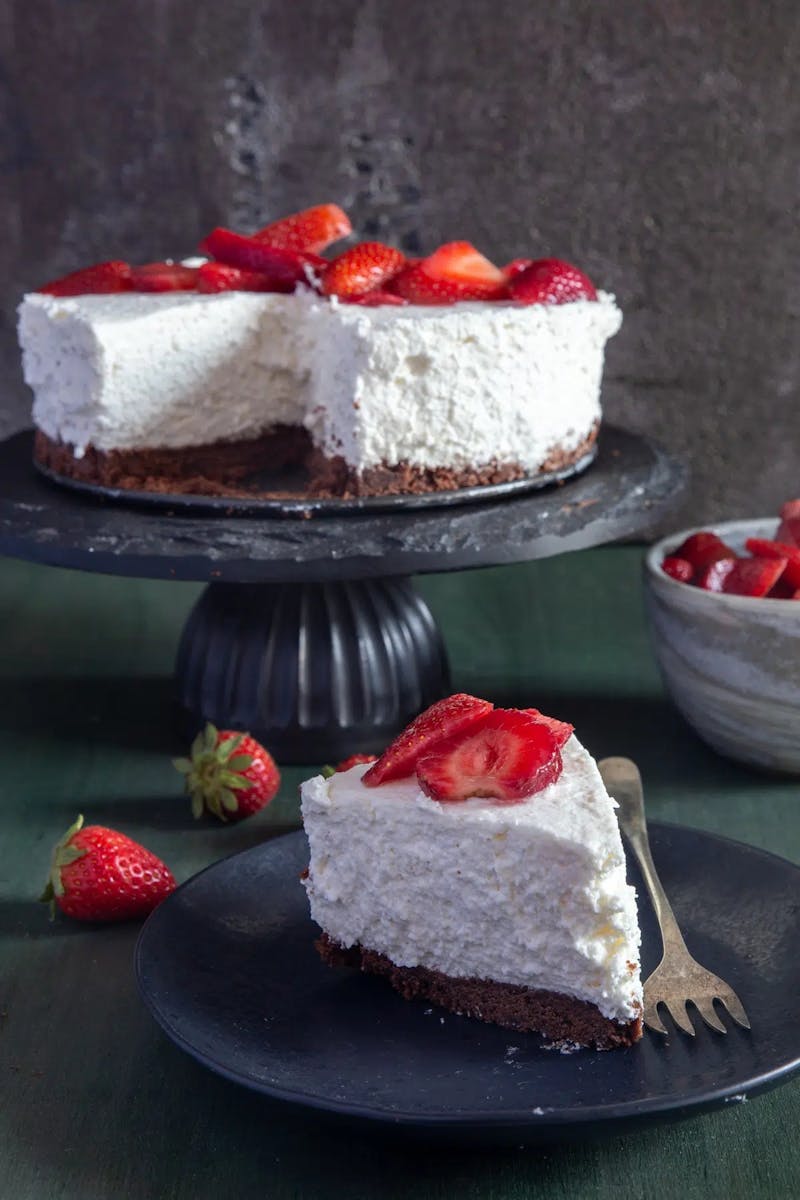 Italian ricotta cheesecake on a cake stand and a slice on a plate.