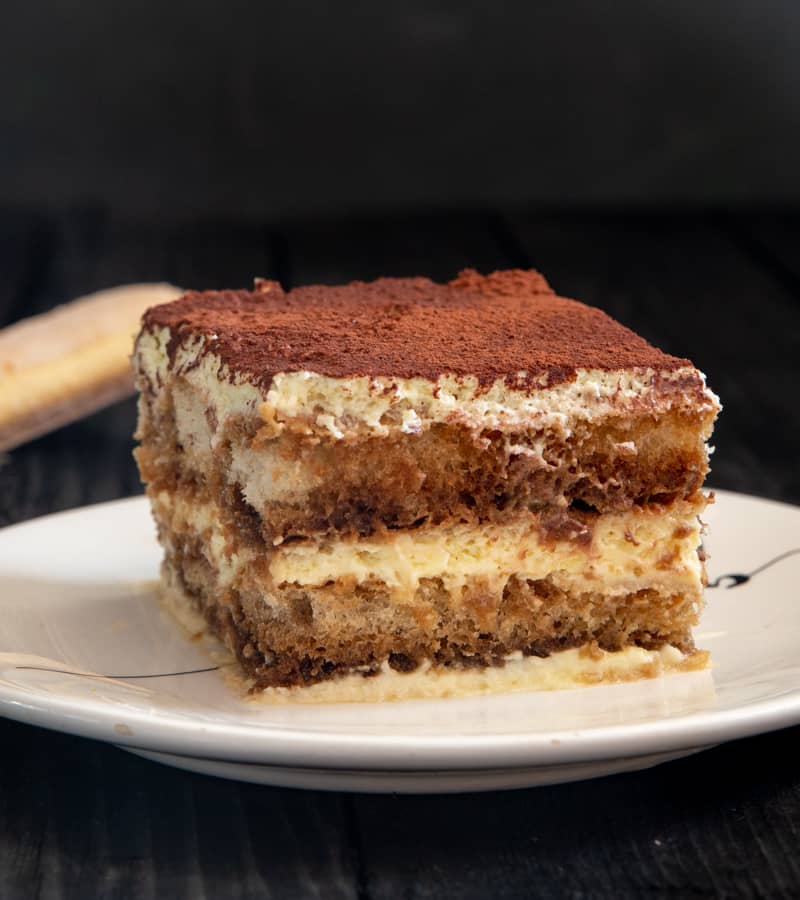 Authentic Tiramisu slice on a white plate.