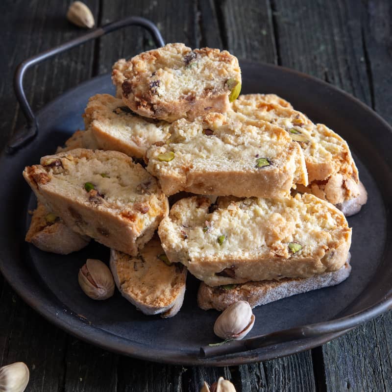 Pistachio biscotti on a black dish.