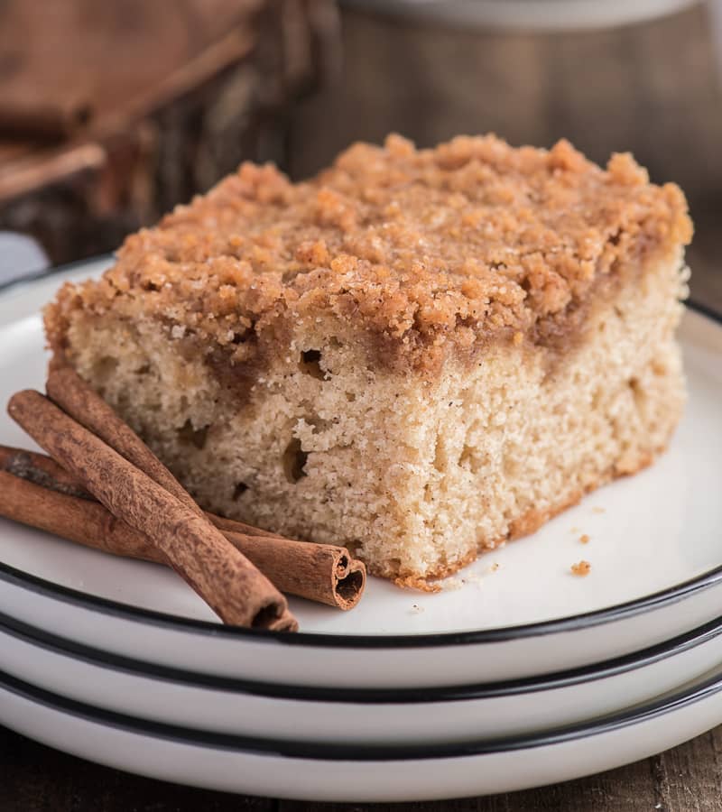 A slice of streusel cinnamon coffee cake on a white plate.