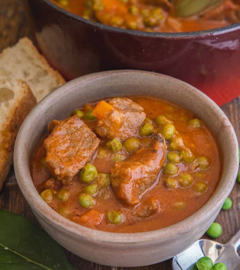 Italian beef stew with peas in a grey bowl.