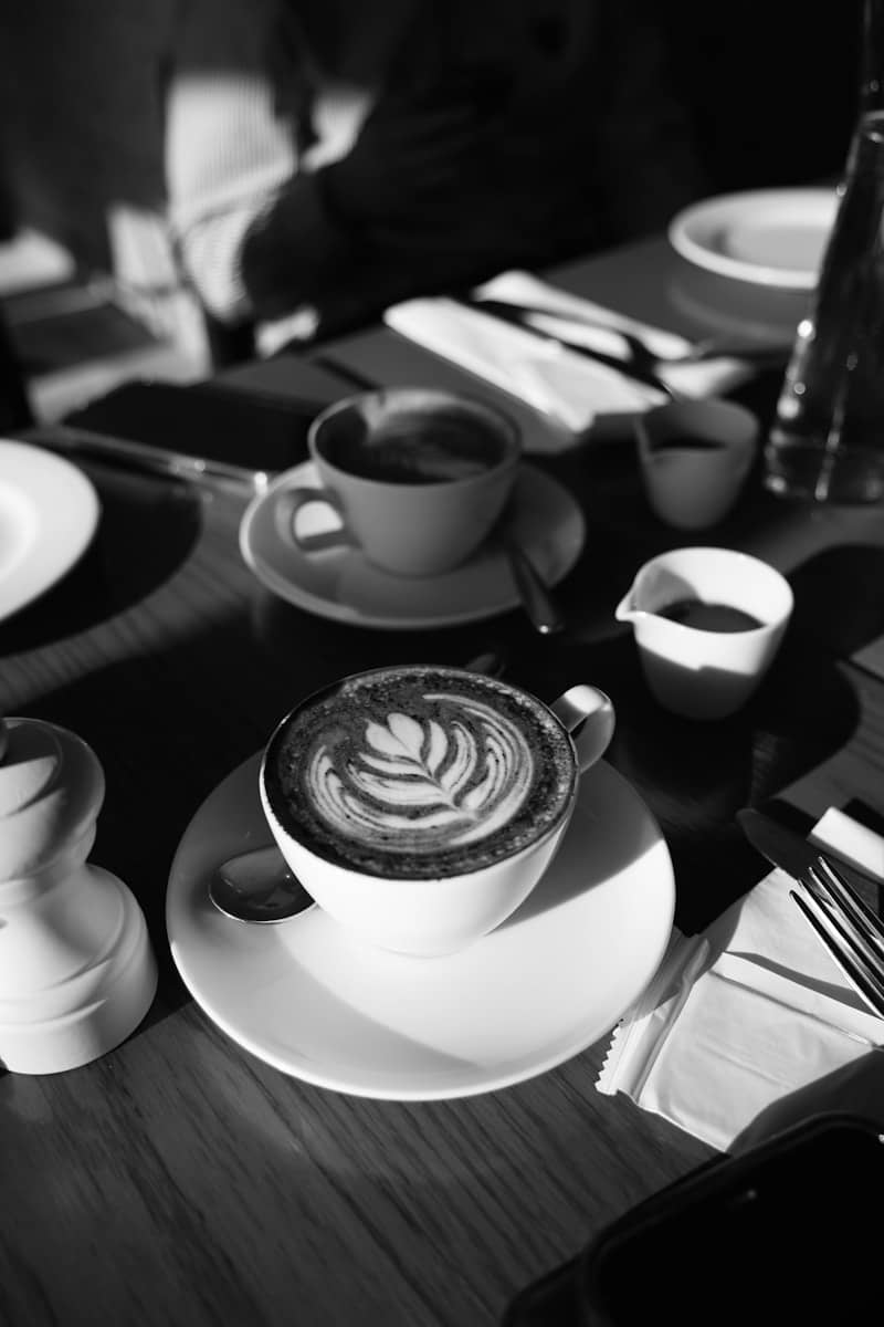 Coffee cups sit on a table in black and white.