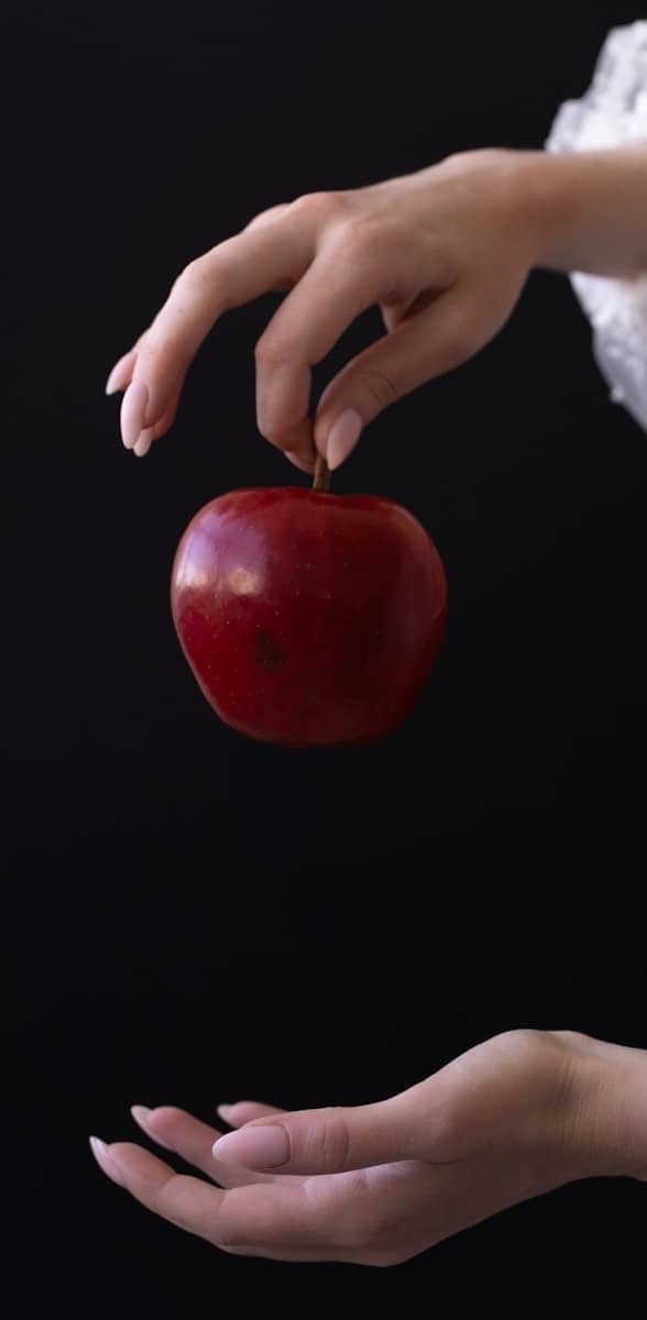 A woman in a white dress holding an apple