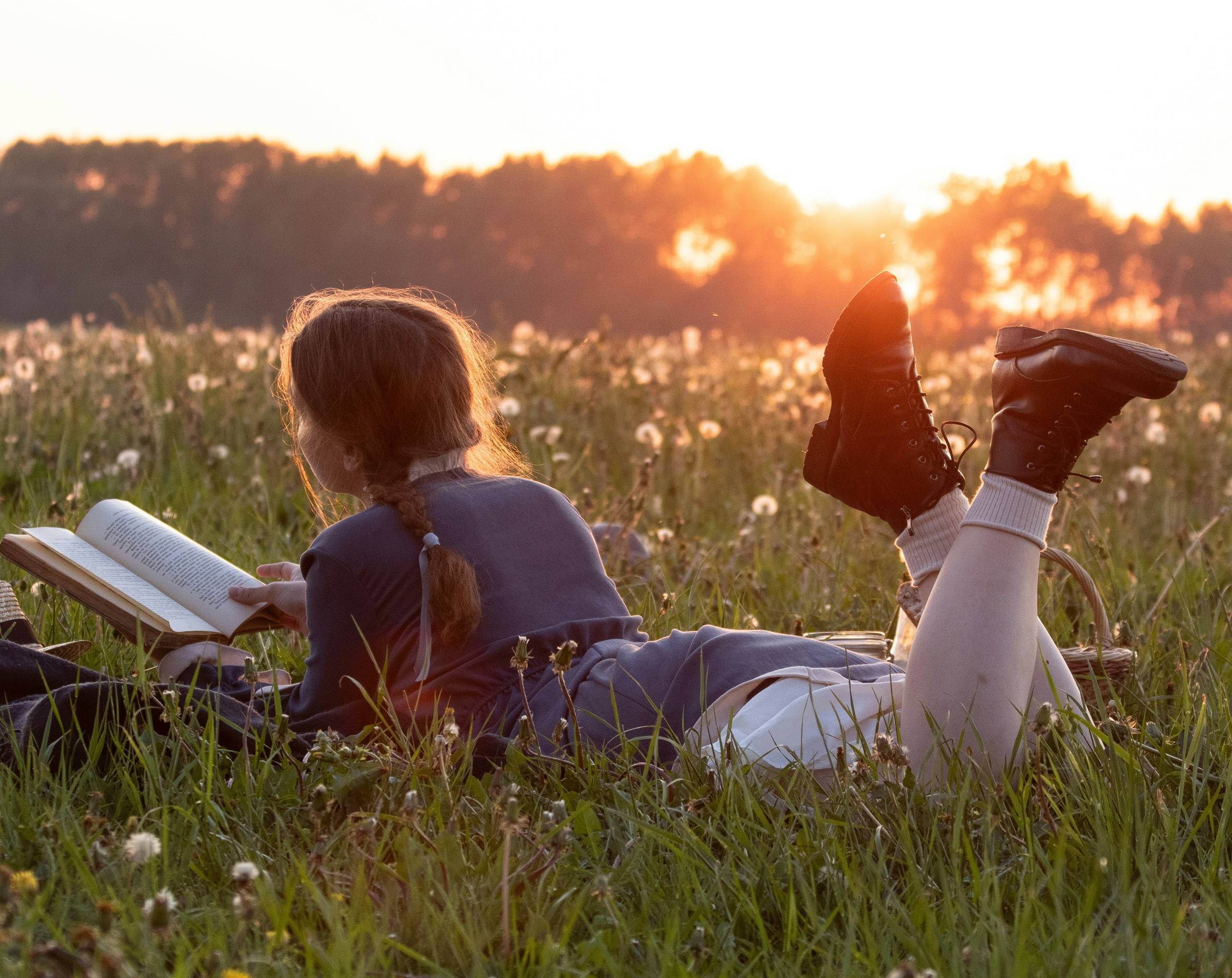 photo of young woman lying reading (photo by Olga Nevajno, Unsplash)  