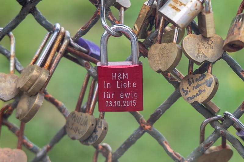 A bunch of padlocks are attached to a fence