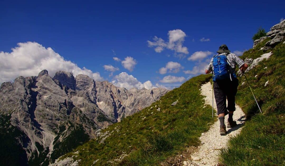 A hiker on a steep incline with a view of mountains in the distance