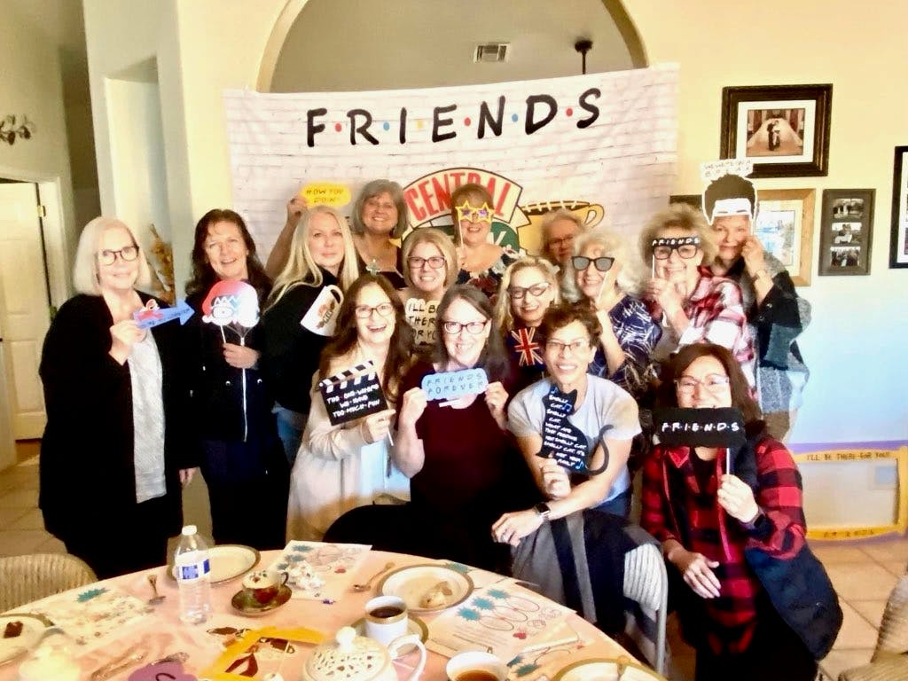 A group of women smiling in front of a FRIENDS banner