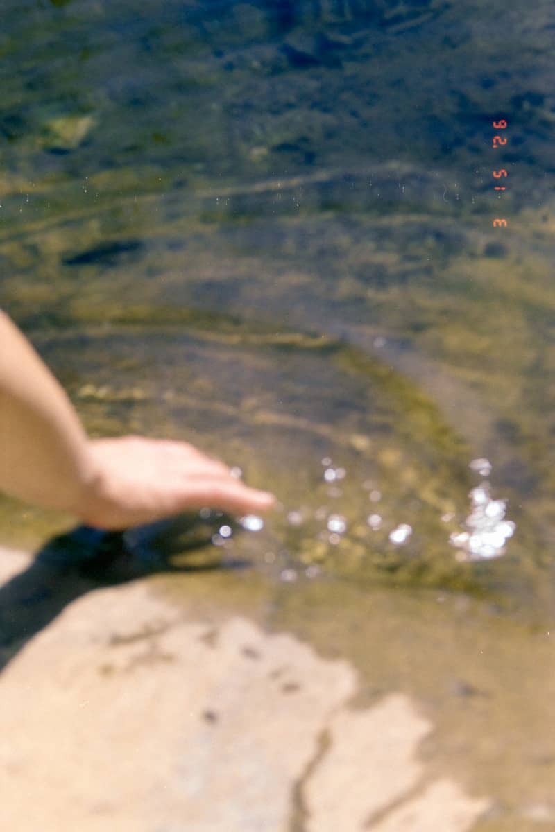 Hand touching clear water with ripples