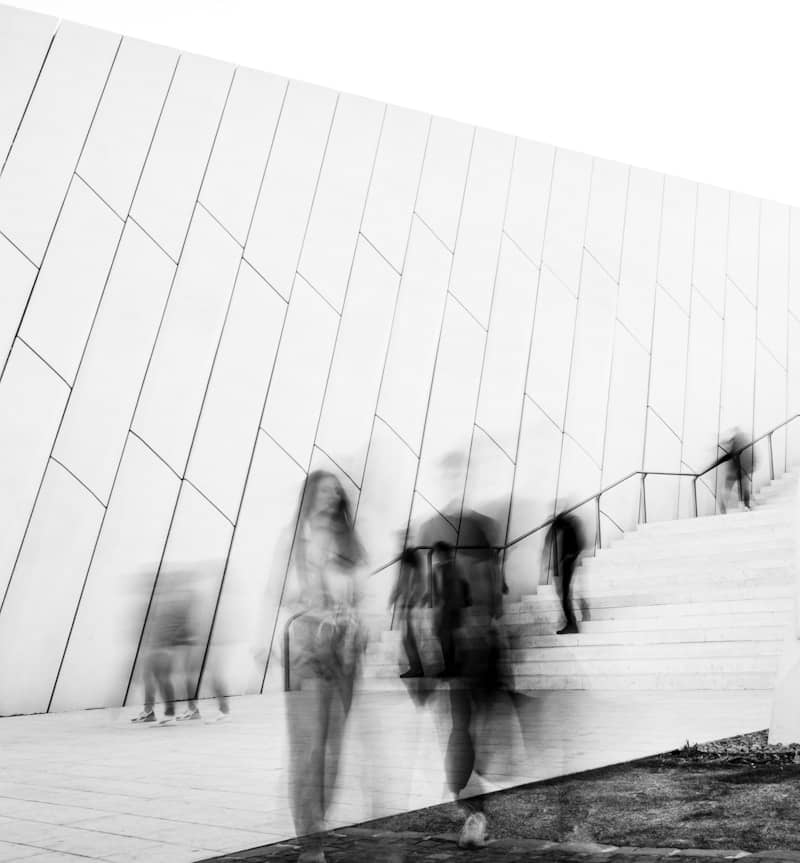 Blurred figures walk up modern white stairs.