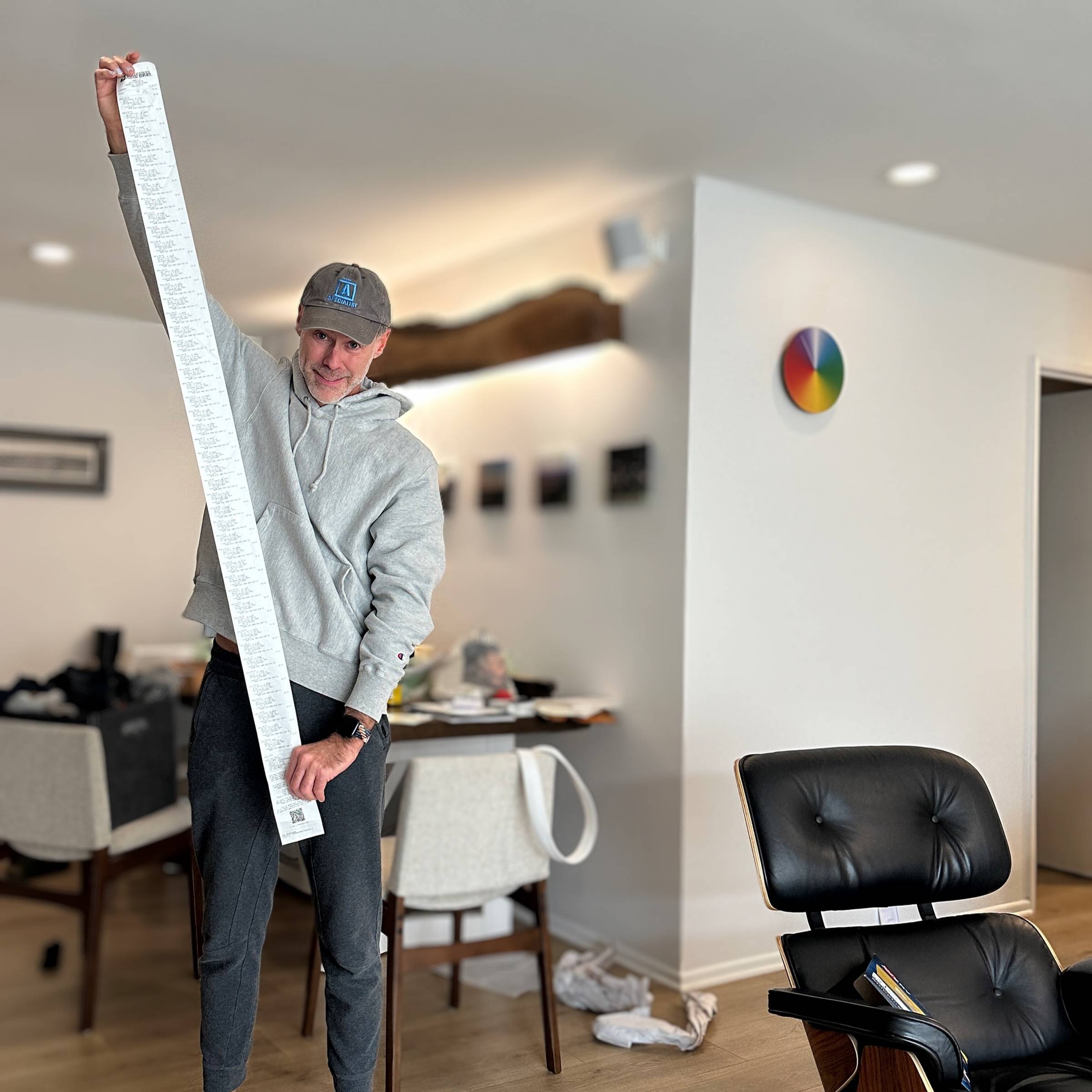 Wearing a ball cap, Roy holds a 4 foot long receipt list