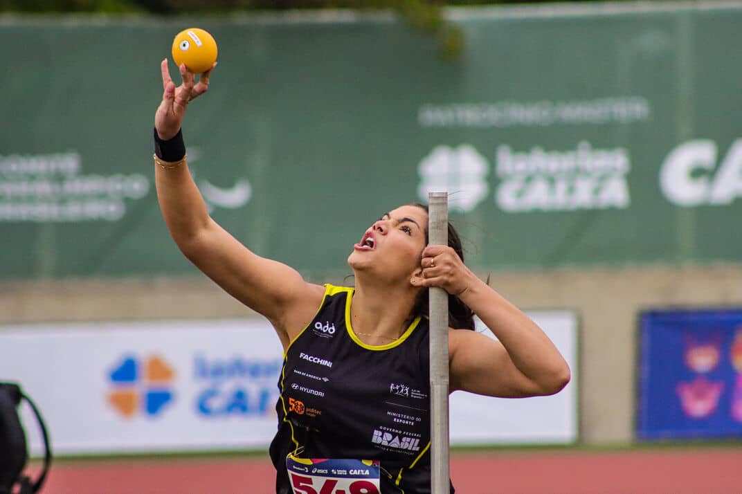 Atleta da ADD com uniforme preto e amarelo no momento do arremesso de peso durante o Circuito Loterias Caixa de atletismo paralímpico