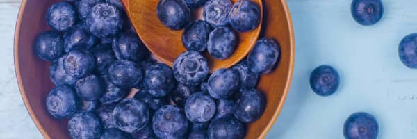 a bowl of blueberries with wooden spoon