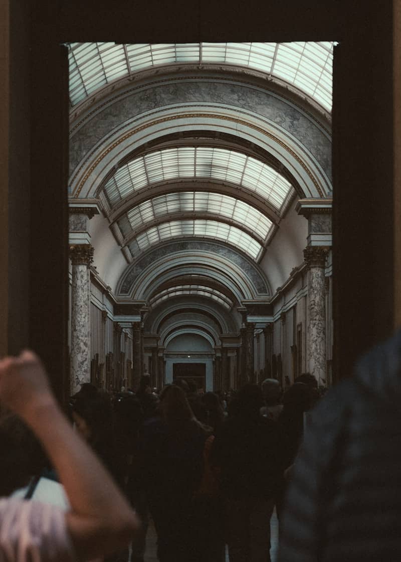 People walk through a grand, arched hallway.