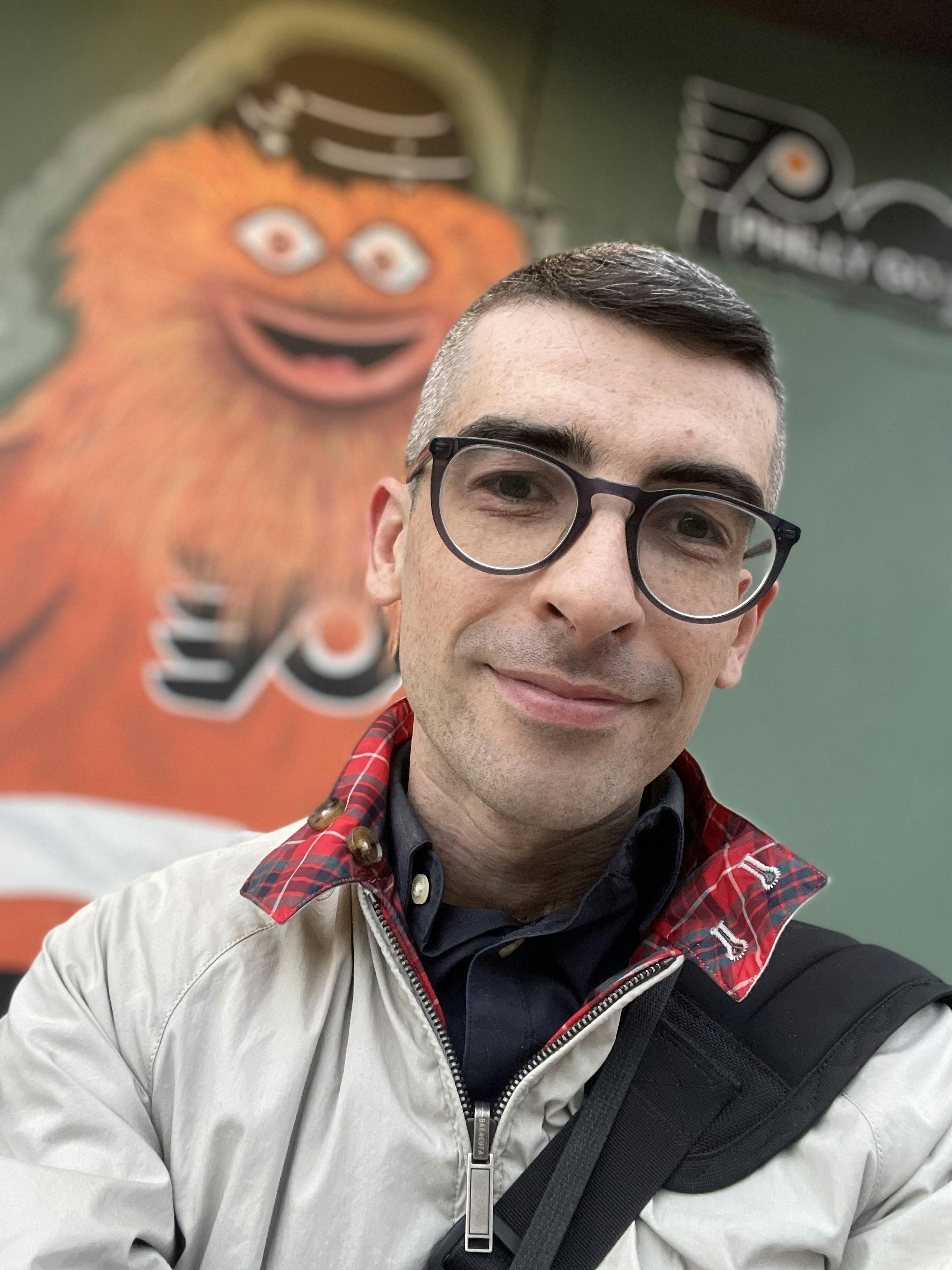 A self portrait with a blurry painting of Gritty, the Philadelphia team’s hockey mascot, looming just out of focus in the background 