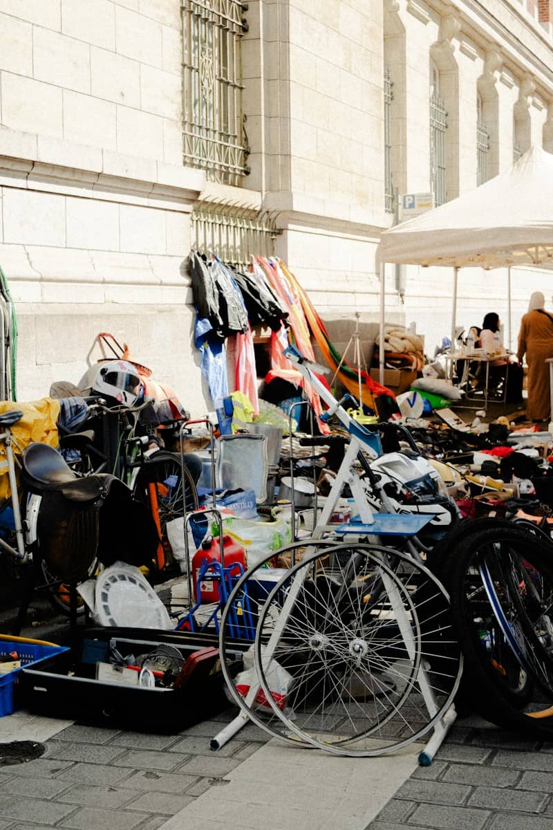 A collection of bicycles, helmets, and miscellaneous items at an outdoor flea market