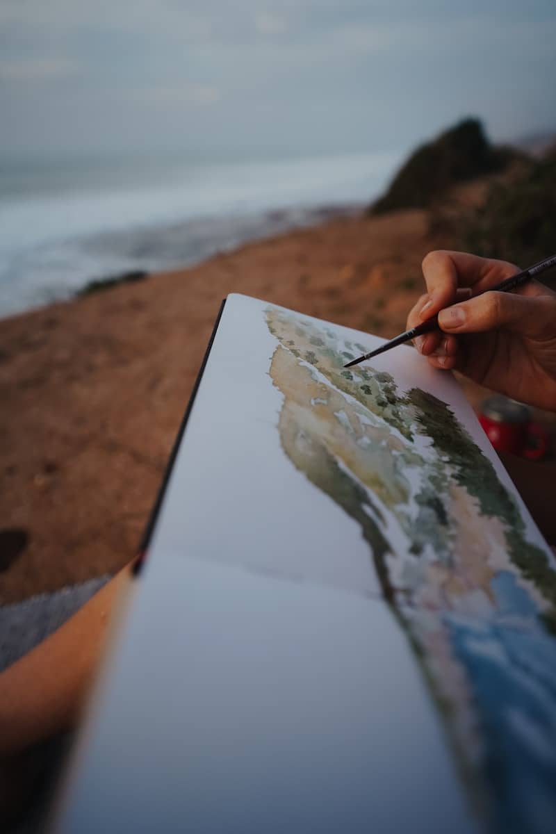 A person is painting a picture on the beach