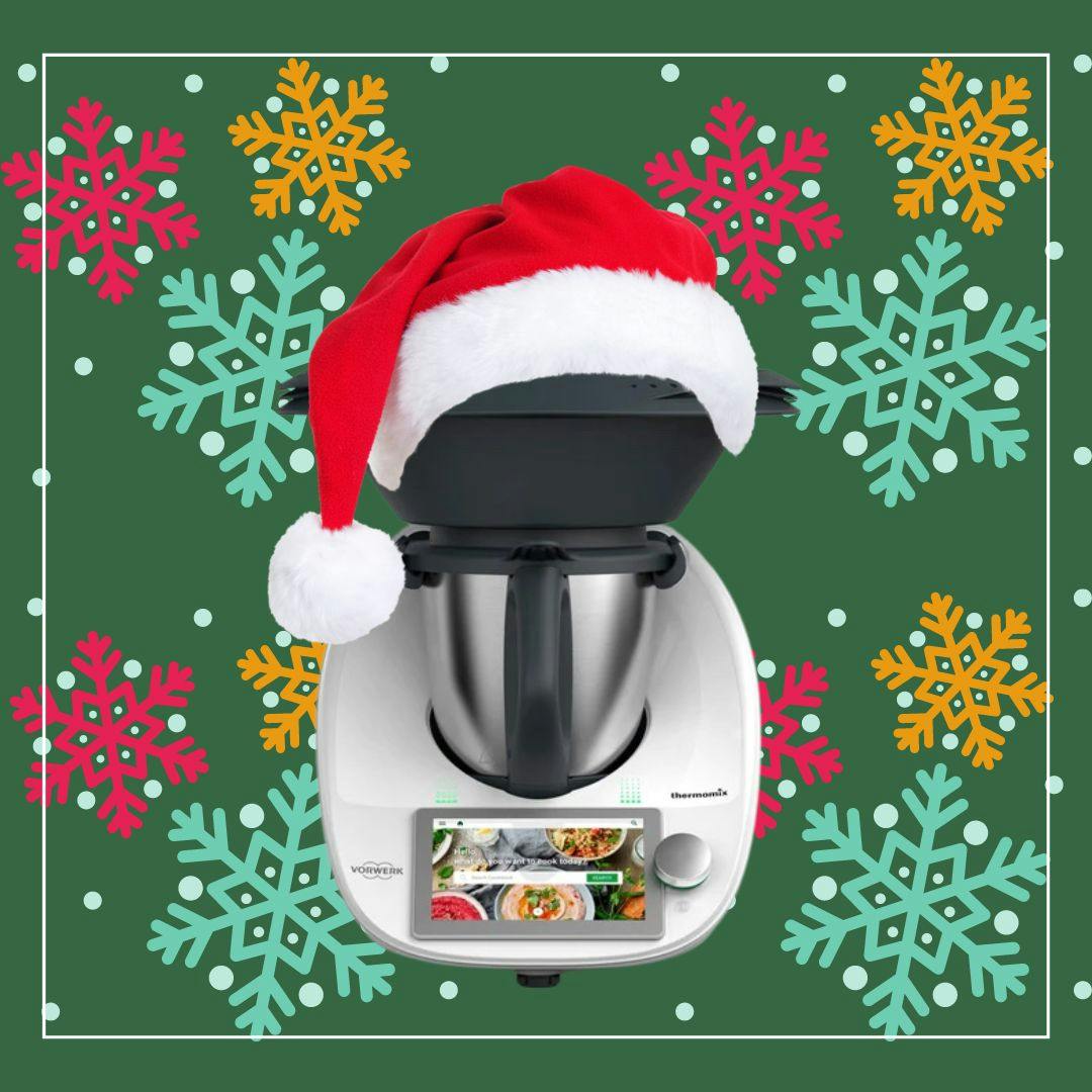 A Thermomix wearing a Santa hat, surrounded by decorative snowflakes