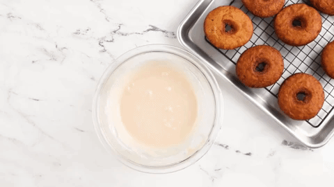 Dipping apple cider donuts in glaze.