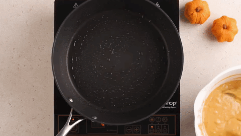 Cooking pumpkin pancakes in a black skillet.
