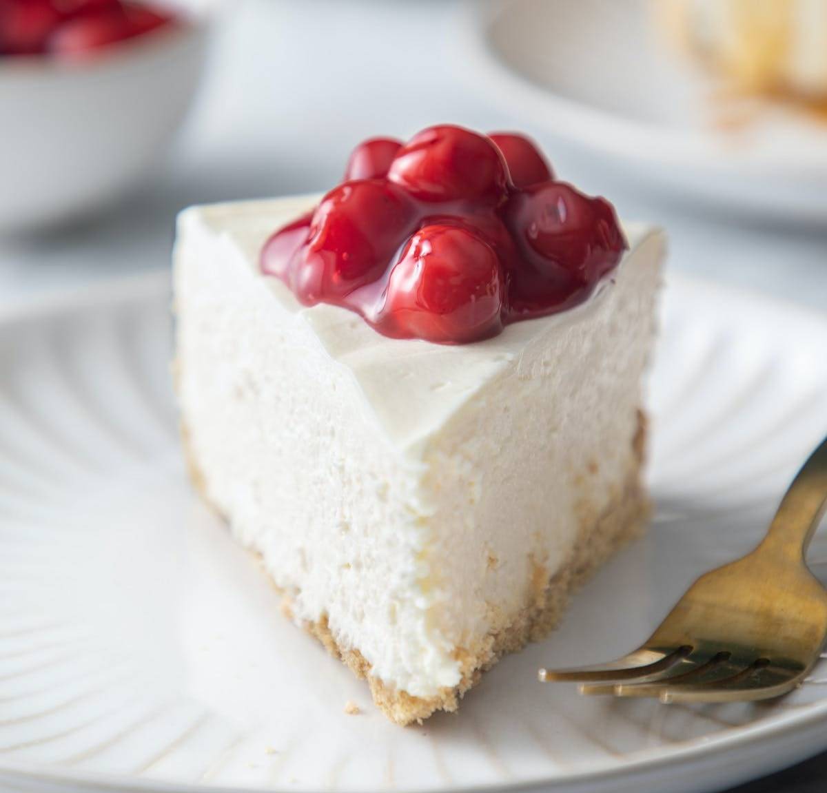 Front view of a slice of no-bake cheesecake topped with cherry pie filling.