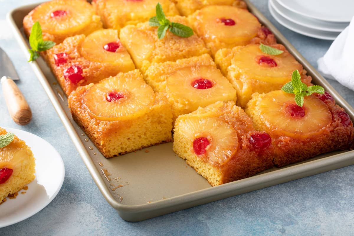 Pineapple upside-down cake on a sheet pan with one slice missing.