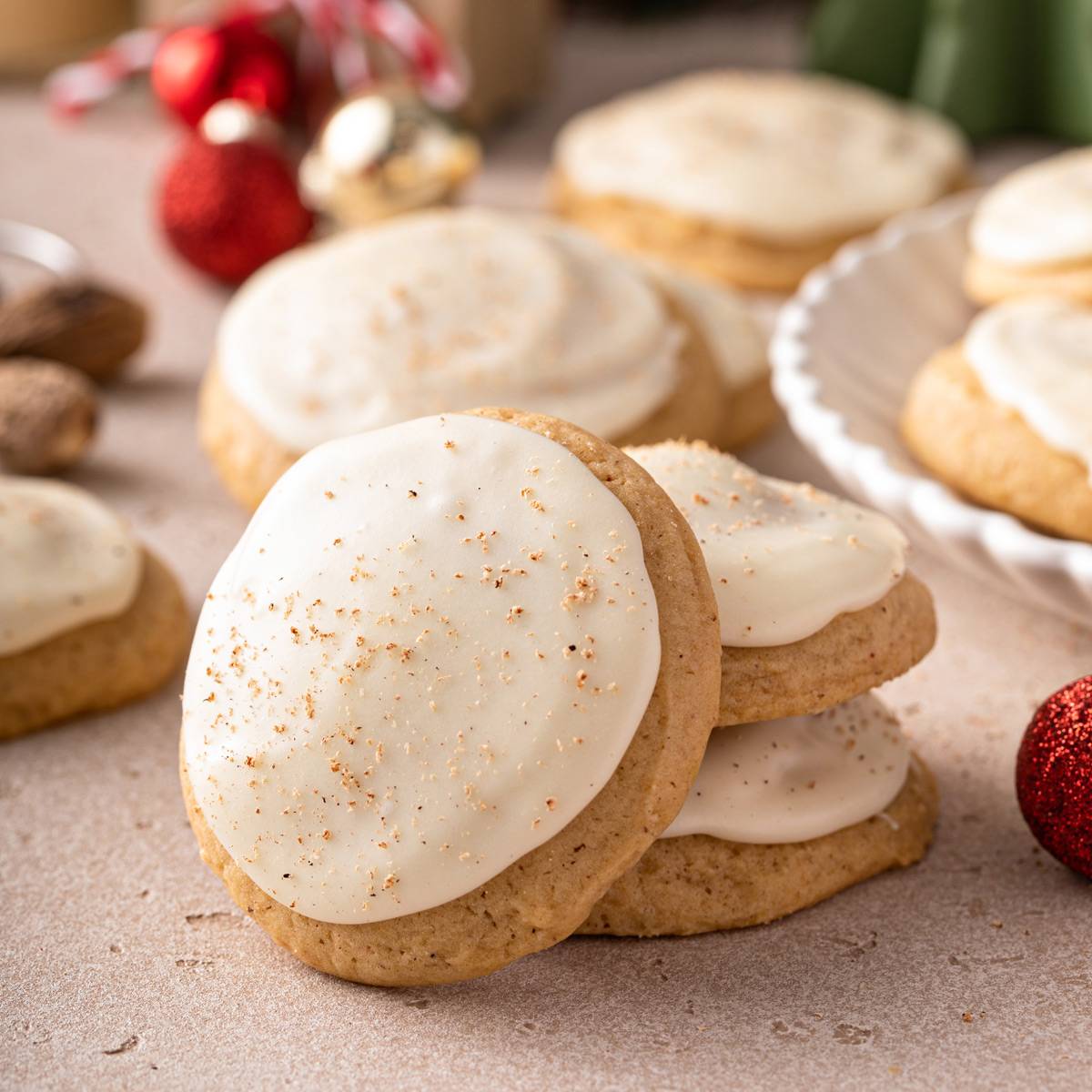 Iced eggnog cookie leaning against two stacked eggnog cookies..