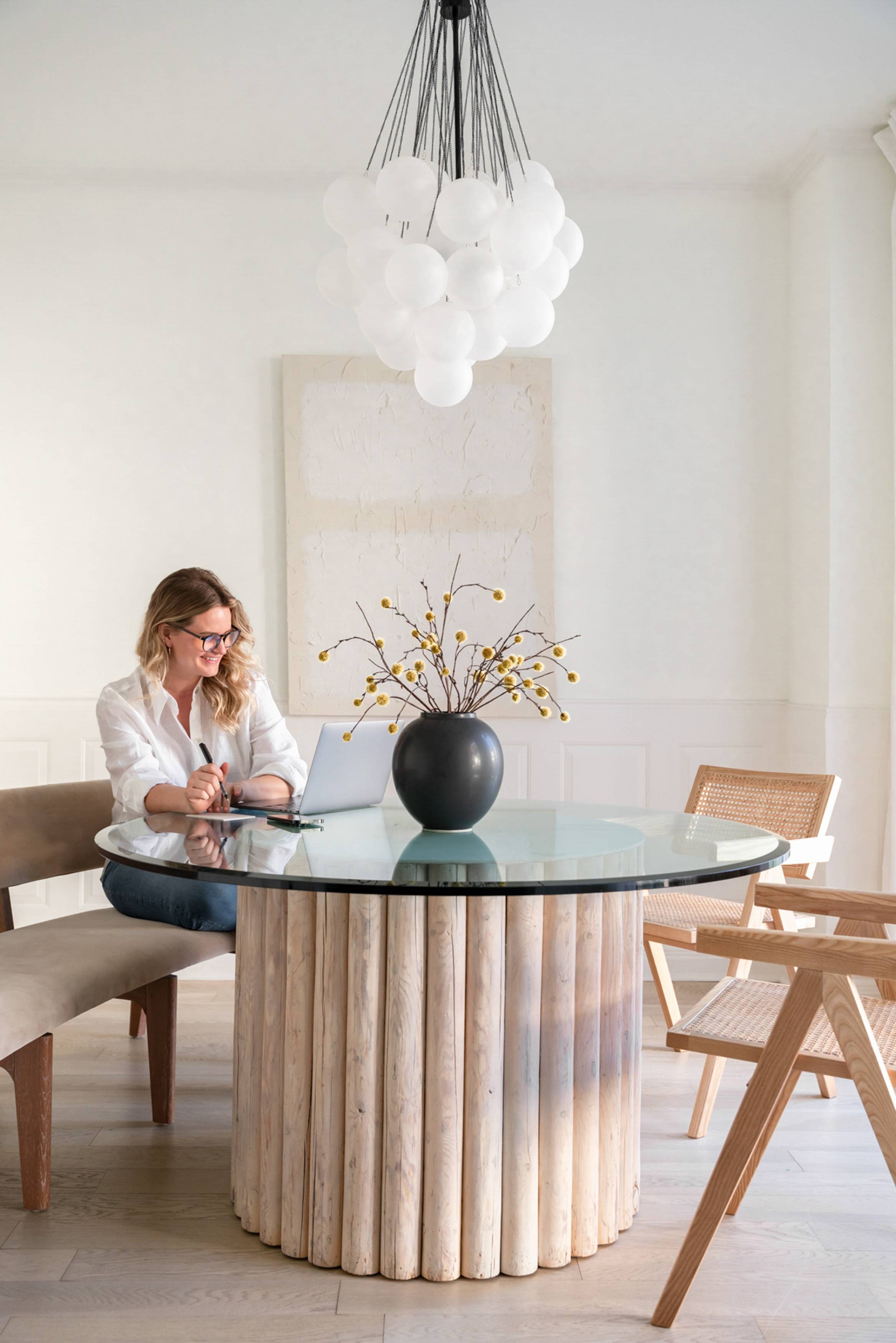 A woman sitting at a table and smiling at a laptop screen