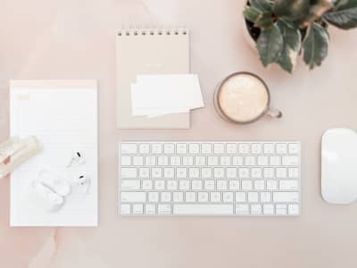 Organized workspace with keyboard, mouse, notebook, and coffee, representing simple content strategy and consistent blogging.