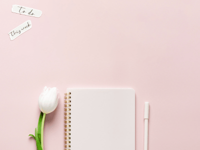 White tulip, spiral notebook, and pen on pastel pink background with “to do” notes, symbolizing audience clarity and focus.