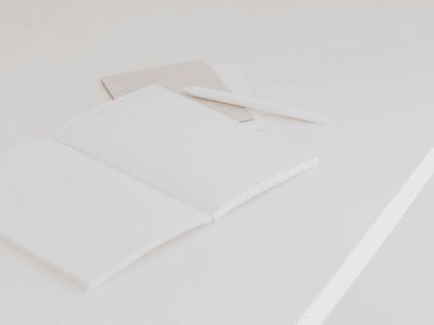 Open notebook with white pen on clean desk, symbolizing fresh start, clarity, and September reset planning.