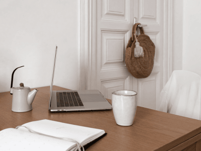 Minimalist workspace with a laptop, coffee mug, and open planner on a wooden desk, creating a calm and focused setting for business growth and productivity.