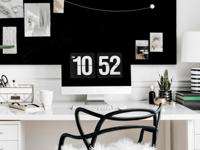 Minimalist home office with computer and vision board—calm workspace for introverted coaches learning to protect your energy in business.