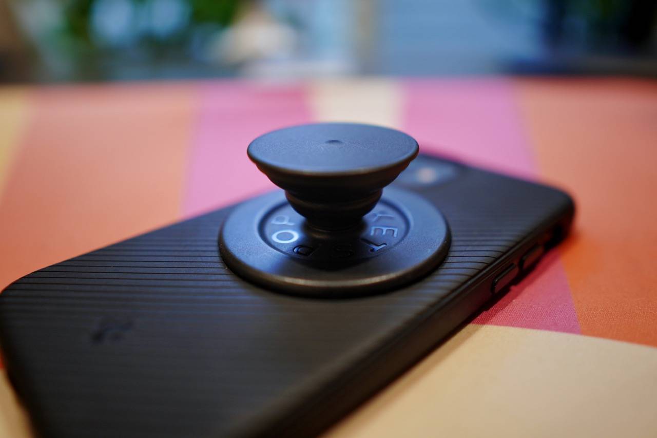 colored desk mat with a black PopSocket attached to the back of an iPhone