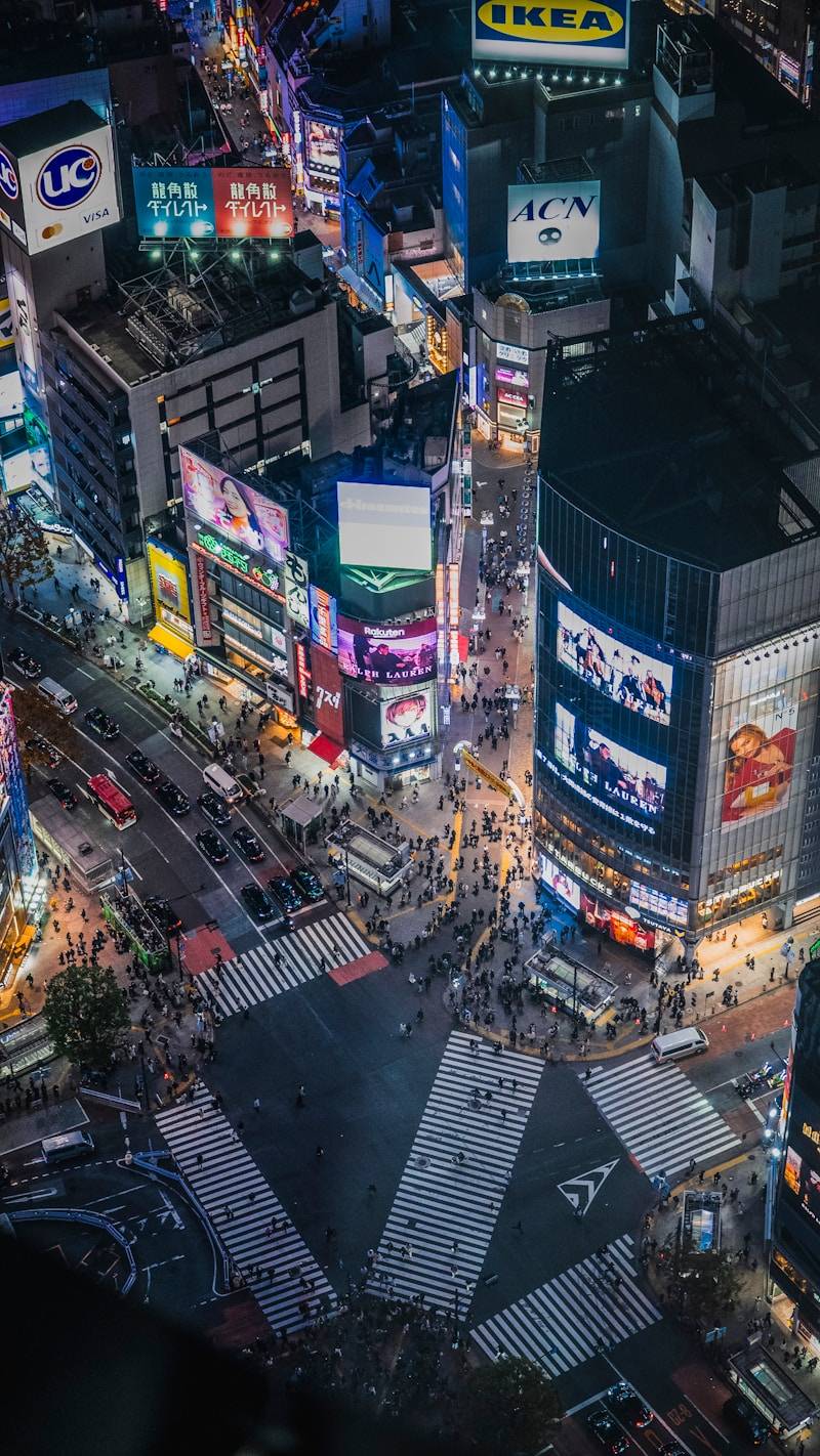 Busy city intersection at night with glowing signs.