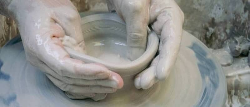 Hands shaping clay on a pottery wheel