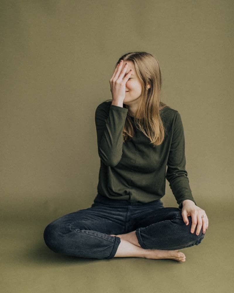 woman in black long sleeve shirt and blue denim jeans sitting on brown wooden chair