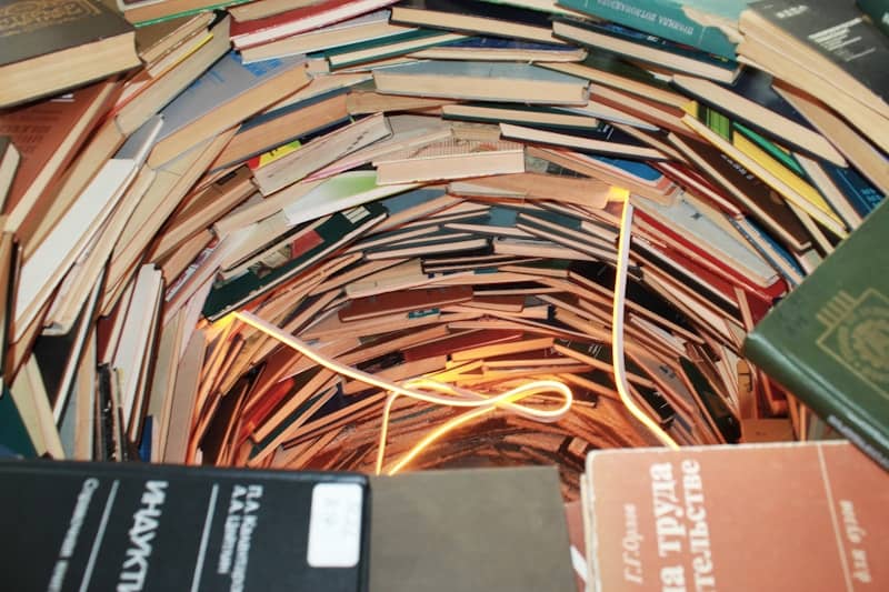 Books form a tunnel, illuminated by a light.
