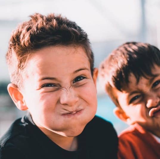 shallow focus photography of two boys doing wacky faces