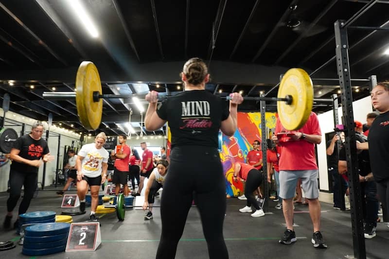 A woman performs a squat with a heavy barbell.