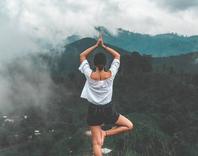 woman standing on rock facing forest