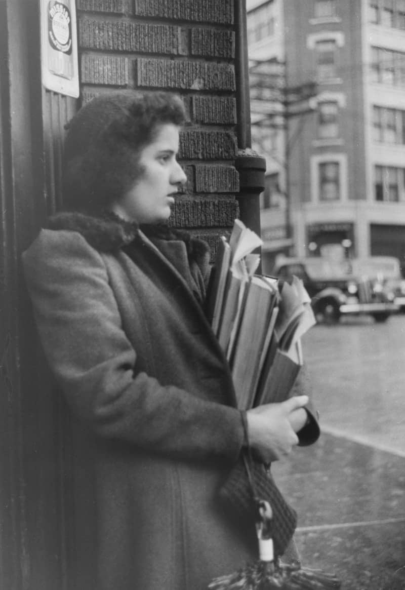 Young woman holding books and papers outdoors.